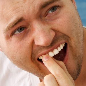 man touching his tooth